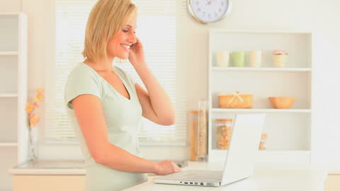 Woman Smiling While Making Phone Call in Kitchen