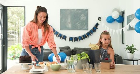 Mother and Daughter Planning Birthday Celebration in Room with Decorations