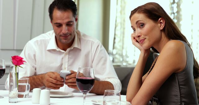 Bored woman waiting for her date to stop texting at a restaurant