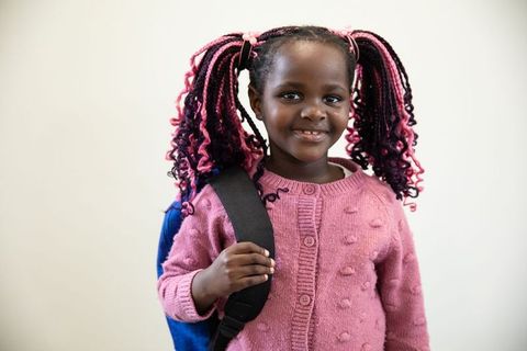 Smiling Child in Pink Sweater Holding Blue Backpack