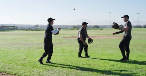 Three Teammates Practicing Catching Baseball During Outdoor Field Training