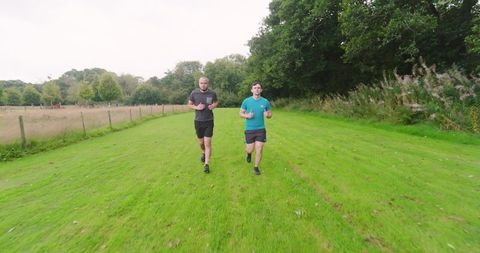 Healthy lifestyle: men jogging in park on grassy path