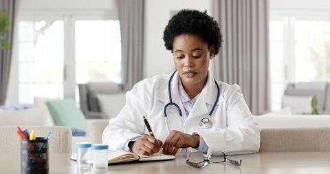Female doctor in lab coat writing medical consultation notes