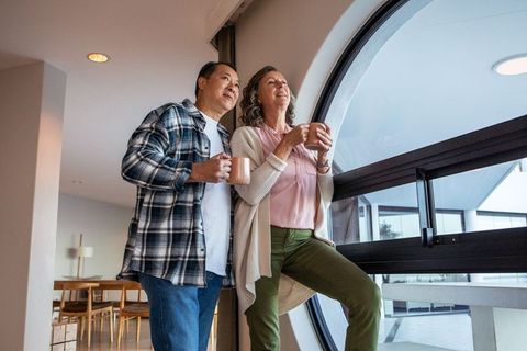 Diverse couple enjoying coffee near modern circular window