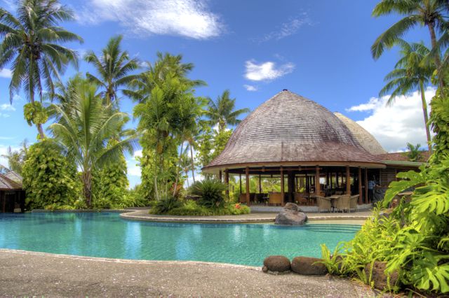 Tropical resort villas feature a beautiful pool surrounded by lush palm trees. Great for promoting luxury travel destinations, vacation packages, summer getaways, and holiday relaxation ideas. Perfect for use in travel blogs, tourism advertisements, brochures, and social media campaigns.