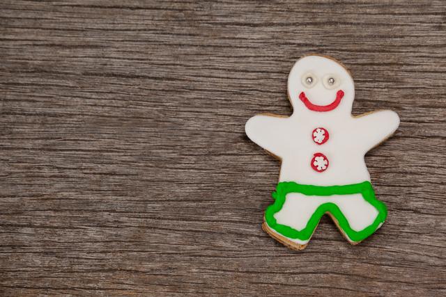 Gingerbread man cookie decorated with icing, placed on a rustic wooden background. Ideal for holiday-themed designs, Christmas cards, festive advertisements, baking blogs, and winter celebration promotions.