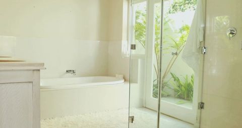 Sunlit minimalist bathroom featuring built-in alcove bathtub and glass shower