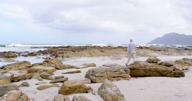 Senior Man Walking on Rocky Beach on Overcast Day - Download Free Stock Images Pikwizard.com