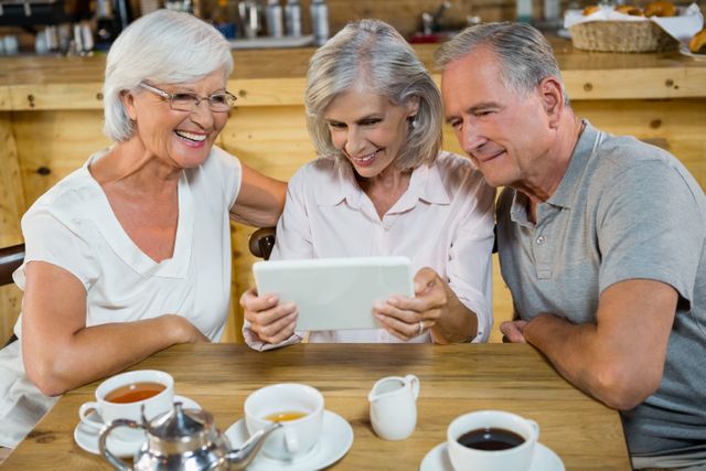 Group of senior friends using digital tablet in cafÃ©