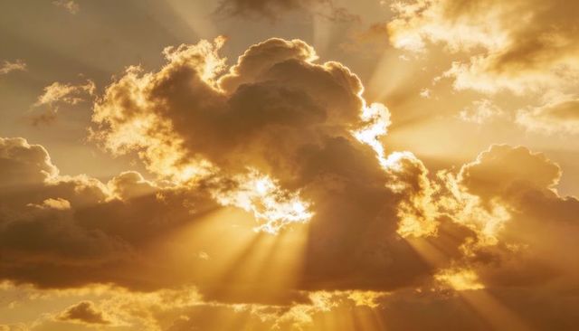 Golden sunbeams piercing dramatic cumulus clouds at sunset with crepuscular rays