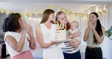 Women Celebrating Birthday with Cake and Candles in Cozy Living Room