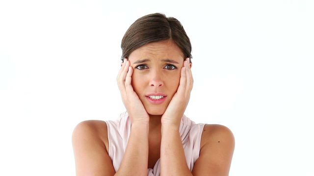 Captures a young woman looking shocked, placing her hands on her cheeks, set against absolute white. Portrays raw emotion of surprise or concern. Ideal for articles about reactions, lifestyle blogs, or emotional marketing campaigns emphasizing unexpected scenarios. Suitable for use in emotional expression studies and psychological insights materials.