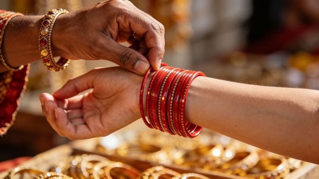 Fastening red bridal bangles on wrist during traditional indian wedding jewelry shopping
