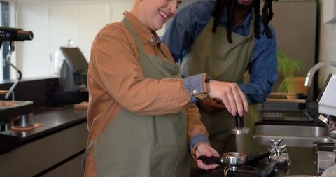 Smiling diverse baristas tamping espresso together at modern coffee bar