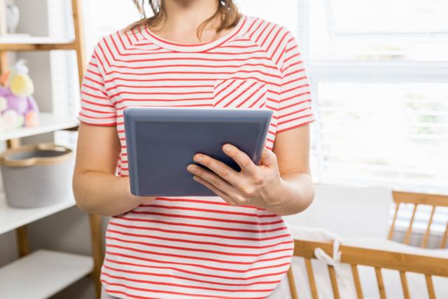 Mid-section of woman using digital tablet at home