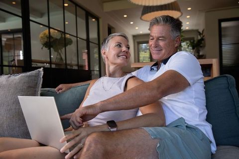 Senior couple enjoying relaxed laptop browsing at home