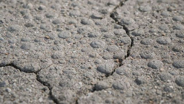 Cracked granular concrete with pebble aggregate and pitted surface texture close-up