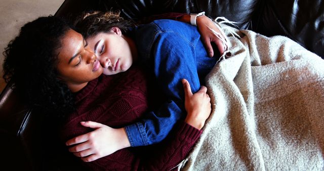 Interracial couple lying on a couch, embracing while napping. Depicts a moment of love, comfort, and relaxation. This can be used in content promoting love, relationships, multiculturalism, relaxation, or intimate moments.