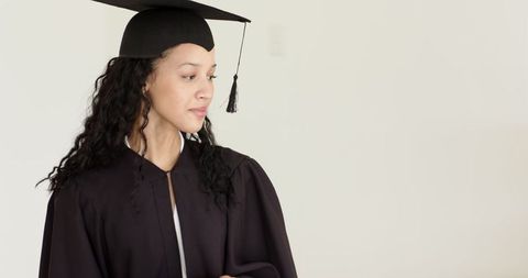 Graduate in cap and gown using tablet for celebration