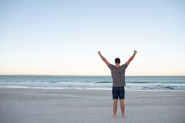 Man Celebrating on Beach with Arms Outstretched - Download Free Stock Photos Pikwizard.com
