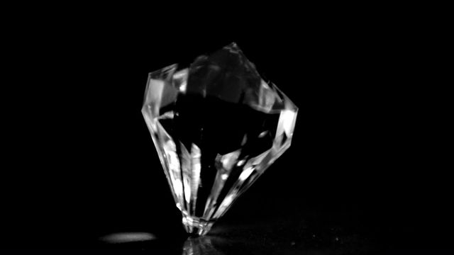 A single diamond is elegantly spinning against a deep black background, showcasing its mesmerizing clarity and shimmer. The focus is on the pristine beauty of the gemstone, capturing the essence of luxury and sophistication. This image can be used to highlight the allure and elegance in high-end jewelry advertisements, luxury brand campaigns, or for artistic projects emphasizing beauty and precision.