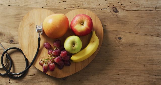Image of close up of stethoscope with fruit on wooden table. global medicine and healthcare concept.