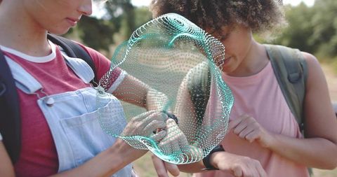 Teen friends checking smartwatch with teal hologram overlay outdoors backpacks wearable