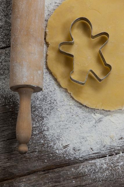 Dough with rolling pin and cookie cutter on a plank