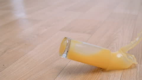 Orange Juice Splashes as Glass Drops on Floor in Slow Motion