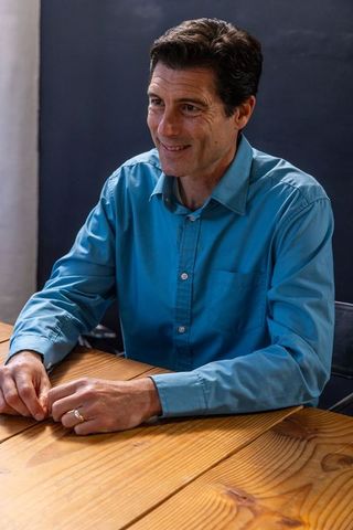 Middle-aged professional man at wooden table displaying wedding ring