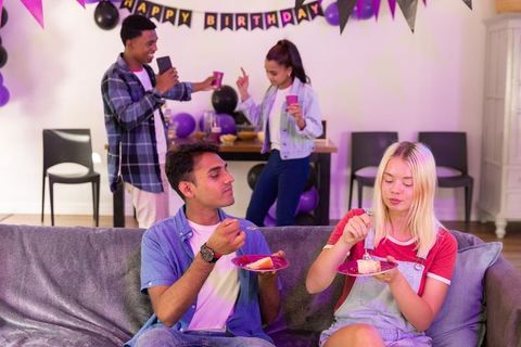 Diverse young friends celebrating birthday party with cake and decorations