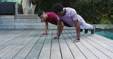Diverse friends exercising outdoors by pool with smartwatches