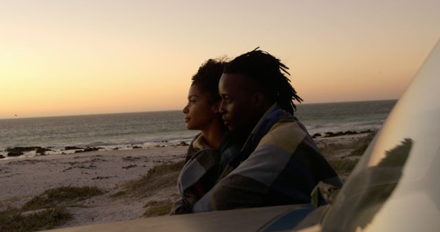 Couple Wrapped in Blanket Watching Sunset by Ocean - Download Free Stock Images Pikwizard.com
