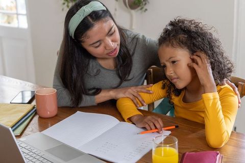 Helping with math homework at kitchen table, parent guiding child through arithmetic