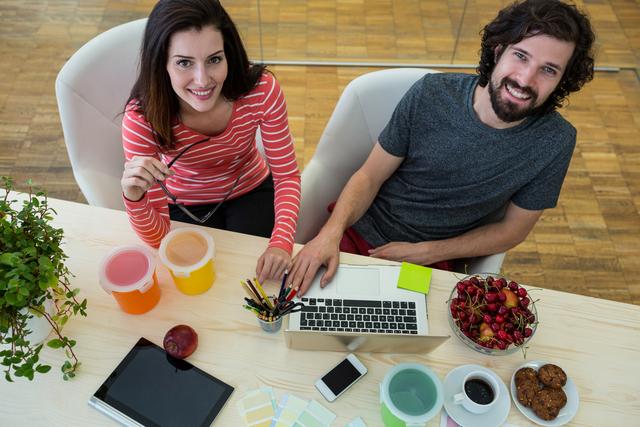 Male and female graphic designers using laptop in office