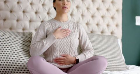 Woman embracing mindfulness through meditation on bed