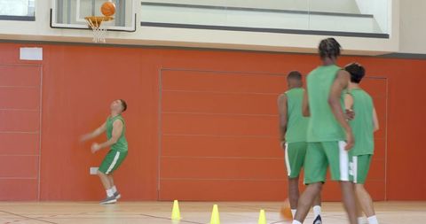 High school basketball players practicing cone dribbling and layup shooting in indoor gym