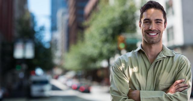 Man in uniform stands confidently with arms crossed in an urban city environment, smiling brightly. Ideal for use in professional services advertisements, career-focused content, or portraying urban workers and job satisfaction.