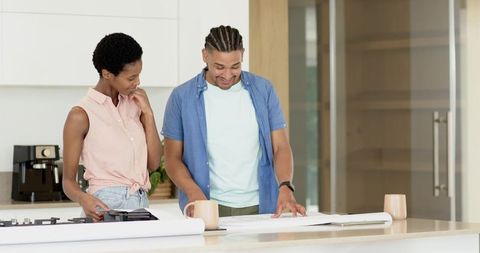 Diverse Couple Discussing Home Design Plans in Modern Kitchen
