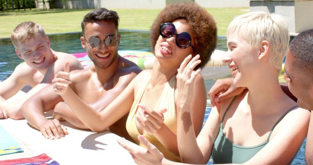 Group of young adults lounging by pool, laughing and enjoying summer. Great for ads, travel promotions, lifestyle blogs, and social media content showcasing friendship and leisure.