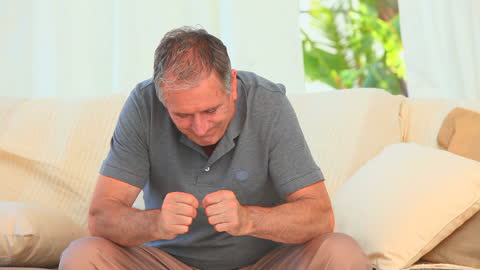 Despairful Man Clenching Fists Seated Indoors