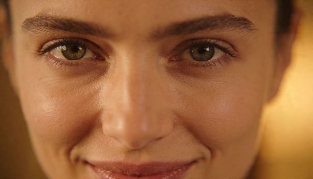 Intimate closeup of woman gazing with hazel eyes, warm smile and natural skin texture