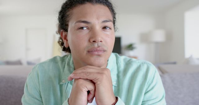 Thoughtful, sad biracial man with long hair sitting on sofa in living room - Download Free Stock Photos Pikwizard.com