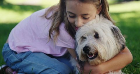 Joyful girl embracing fluffy dog in lush green park