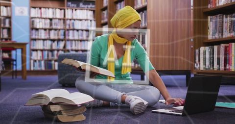 Woman in hijab studying in library with technology adjacency