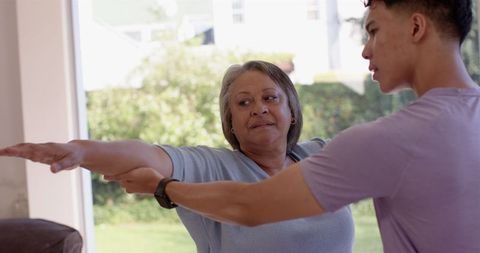 Assisting Senior Woman with Arm Exercise Guidance by Male Physiotherapist