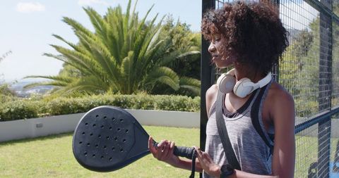 African american woman holding padel racket wearing headphones preparing for match