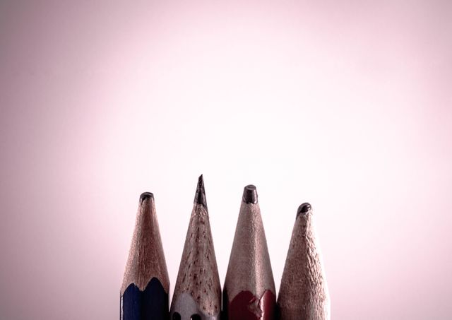Detailed close-up of four well-sharpened pencils displaying individual unique markings against pink background, ideal for educational content, creative art projects, and promotional material for school supplies.