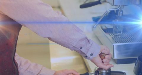 Barista pressing tamper at espresso machine hands closeup with warm lens flare
