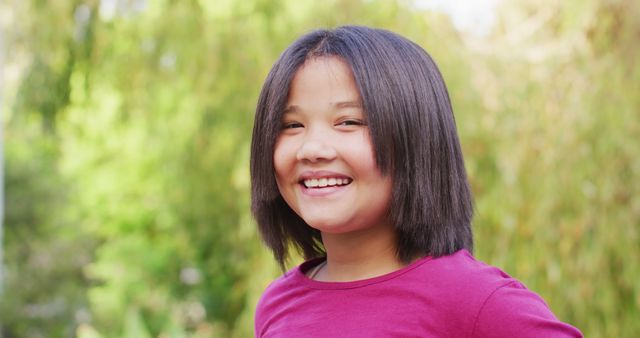 Smiling young girl with short hair standing outdoors with a nature background. Great for portraying childhood joy, confidence, and youthful spirit. Suitable for educational materials, advertisements, or blog articles about parenting and child development.